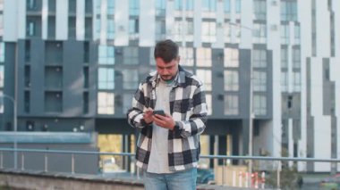 İletişim sinyalini ve interneti cep telefonuyla yakalamaya çalışan orta yaşlı bir turist şehir merkezinde daha iyi bir bağlantı için telefonu kaldırdı. Şehirde hayal kırıklığına uğramış beyaz bir adam var..