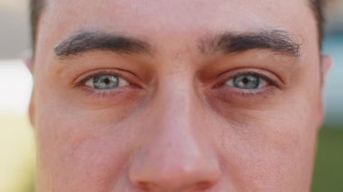 Yakın çekim makro portresi. Doğal olgun, yakışıklı erkeklerin gözleri. Kameraya bakıp gülümsüyor. Erkek yüzünün çekici gri gözleri, yetişkin erkek modeli. Kafkas turistin geçmişi bulanık. Yaşam Tarzları.