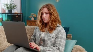 Evde dizüstü bilgisayarla oturan genç bir kadın beklenmedik olumlu haberlere şaşırdı. Kanepedeki beyaz saçlı kız internetteki ilginç keşfe merak ve neşe ile tepki veriyor.