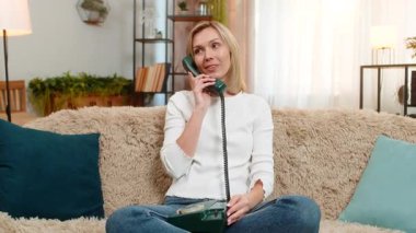 Orta yaşlı bir kadın evde eski moda telefon kullanıyor, duygusal konuşuyor ve hayal kırıklığı içinde el sallıyor. Yetişkin kadın yoğun tepki gösteriyor, tartışırken ya da tartışırken gözle görülür bir tutku ve mizah ile