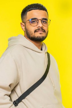 Neşeli, sevimli, mutlu, mutlu Hintli adam kameraya bakıp rahatlama hayali kuruyor. İyi haberler veriyor. Sarı stüdyo arka planında izole edilmiş Arap Hindu sakallı adam.