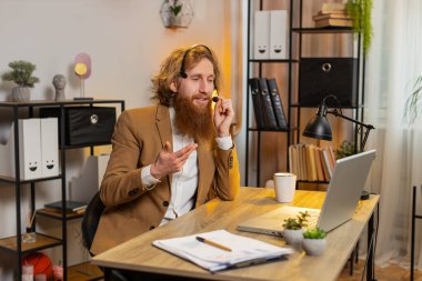 Kafkas işadamı kulaklık takıyor, serbest çalışan, çağrı merkezi ya da destek operatörü yardım hattı, müşteri ya da iş arkadaşı iletişim desteği ile konuşuyor. Kızıl saçlı adam ofis masasında oturuyor.