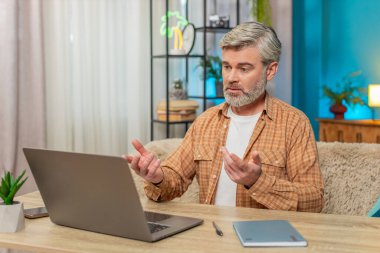 Beyaz, olgun bir adam önemli bir iş kamerası görüşmesi yapmak için dizüstü bilgisayar kullanıyor. Adam ciddi odaklanmış görünüyor, tartışma sırasında aktif hareket ediyor, internetten video görüşmesi.