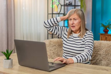 Olgun kadın evdeki dizüstü bilgisayarında sistem hatası virüsü yaşıyor. Kafası karışmış görünüyor, parmaklarını klavyeye vuruyor, başarısız oluyor, kaybediyor, veri kaybından duyduğu gerilimi dile getiriyor.