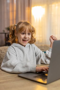 Dizüstü bilgisayara bakan, klavye yazan genç bir kız büyük bir hevesle çevrimiçi programlamayı öğreniyor. Çocuk, olumlu sonuç elde ettikten sonra heyecan içinde eğitim çalışmasında ilerleme kaydederek kutluyor