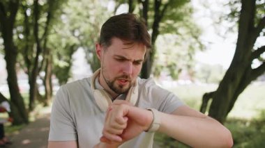 Kaçak akıllı saat zamanlayıcısı çalıştırıyor ve çalışıyor. Adam koşmadan önce kalp atış hızını kontrol ediyor. Erkek kardiyo çalıştırmaya başlar. Şehir parkındaki spor bilekliğinin nabzını kontrol et..