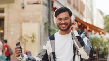 Kablosuz kulaklık takan mutlu Hintli adam dışarıda dans eden enerjik disko rock n roll müziği dinliyor. Şehir caddesinde yürüyen İspanyol genç bir turist. Yaşam Tarzları.