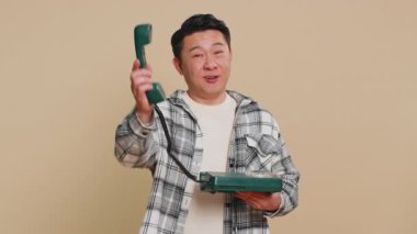 Hey sen, beni ara. Asyalı orta yaşlı bir adam 80 'lerin reklam önerisi olan sabit hatlı bir telefondan konuşuyor. İnternetten alışveriş yapıyor. Bej arka planı olan olgun bir Çinli.