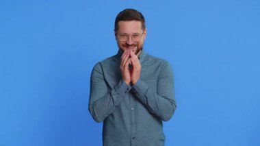 Sinsi, kurnaz, orta yaşlı, gözlüklü, hilekar, şakacı, sinsi, sinsi, sinsi, sinsi, orta yaşlı adam. Mavi arkaplanda izole edilmiş adam