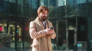 Heyecanlı Hintli işadamı cep telefonuyla şehir merkezinde şok olmuş bir erkek kazandı. Akıllı telefon bahsi zafer başarısını kutluyor. Şehir merkezindeki sokakta duran adam.