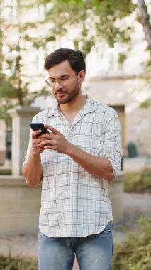 Hintli genç adam sosyal medya uygulamasında akıllı telefon kullanarak kısa mesajlar yazıyor, internette sörf yapıyor, dinleniyor, dışarıda mola veriyor. Şehir caddesinde duran İspanyol adam. Dikey