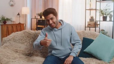 Gibi. Mutlu, heyecanlı Hintli adam kameraya bakıp olumlu bir işaret veriyor. İyi haber, olumlu geri bildirim gibi. Oturma odasındaki kanepede oturan genç Arap adam..