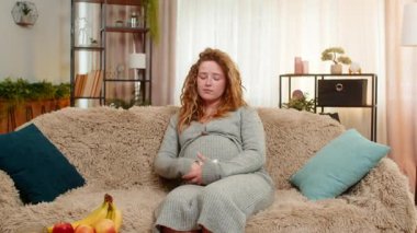 Hamile, üzgün bir kadın, evinde, kanepeye oturup nazikçe karnını tutar, duygusal ifadeyle gözyaşlarını siler, duyarlı ve düşünceli hisseder. Kız anneliğin zorluklarını ve derin duygularını benimsiyor..