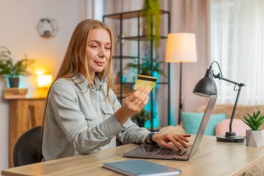 Banka kredi kartı ve dizüstü bilgisayarını merkez ofisteki online alışveriş ödemeleri için kullanan Kafkasyalı mutlu bir serbest kadın. İş anlaşması. E-bankacılık uygulaması ile gülümseyen kız alışverişi.