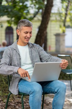 Mutlu olgun bir adam, şehir caddesinde bir sandalyede otururken dizüstü bilgisayarı açar. Kafkasyalı adam defter üzerinde çalışıyor, mesajlar gönderiyor, online alışverişler yapıyor, film izliyor. Kasaba yaşam tarzları. Dikey