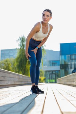 Atletik formda ve kas ağrısı çeken bir kız. Şehir parkında koşarken masaj yapan, travma geçiren genç bir kadın. Fitness dişisinin burkulması şiddetli ağrı germe kuvveti. Bacağa kramp girdi..