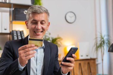 Para transfer ederken banka kartı ve akıllı telefon kullanan, internet üzerinden alışveriş yapan, merkez ofisteki masada oturan Kafkasyalı genç bir serbest çalışan. Uzaktan kumanda işinde çalışan gülümseyen yakışıklı adam..