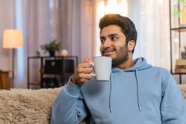 Gülümseyen Hintli adam evde sıcak kahve ya da bitki çayı içiyor. İspanyol adam moladan zevk alıyor, sabahları kanepede oturuyor, düşünceli bir şekilde uzaktan bakıyor ve dinleniyor..