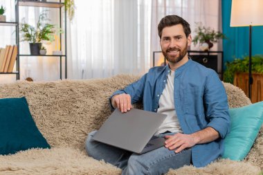 Evdeki genç adam işini bitirdikten sonra bilgisayarını kapatırken memnuniyetle gülümsüyor. Kanepede oturan beyaz adam kendini başarılı, rahatlamış ve projelerini tamamlamaktan mutlu hissediyor.