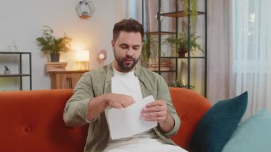 Kahverengi saçlı, açık zarf zarflı mutlu adam mektubu okuyor. Kariyer büyümesi terfi, banka kredisi onayı, üniversite parasal ödülüne başarılı giriş davetiyesi harika haber, piyango kazananı.