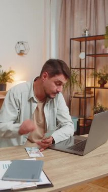 Planlama bütçesi. Zengin, mutlu bir adam Ukrayna 'nın Hryvnias UAH nakitini ev masasında dizüstü bilgisayarla hesaplıyor. Adam gelir maaşından memnun. Planlı tatil hediyeleri için para kazanıyor.