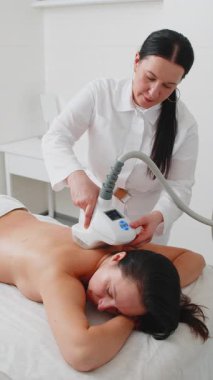 Kozmetikçi doktor sırtında LPG elektrikli süpürge masaj prosedürü uygular. Spa salonundaki kadın figürleri düzeltiyorum. Vücut şekillerini geliştiriyor. Kilo kaybı, lenf boşaltma.