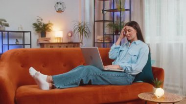 Dizüstü bilgisayar kullanan yorgun genç bir kadın, baş ağrısı, tansiyon ve migren sorunu, evde stres. İnternette çalışan, mesaj yollayan, online alışveriş yapan, film izleyen bir kız. Yaşam Tarzları.