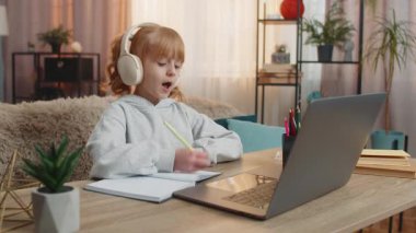 Kablosuz kulaklık takan genç bir kız evde yeni kelimeleri yüksek sesle tekrarlayan İngilizce dersini dinliyor. Beyaz çocuk telaffuza odaklanıyor, öğrenirken konsantrasyon zevkini ifade ediyor