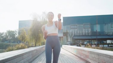 Atletik formda koşucu başarıyı kutluyor. Çığlık atıyor. Zafer maratonunu kutluyor. Güneşli şehir parkında kardiyo eğitimi. Genç bir kadın sağlıklı yaşam tarzını seviyor. Aktif sporcu kadın motivasyonu.