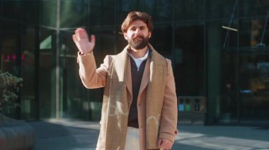 Neşeli Arap turist, kameraya gülümseyen, el sallayan, el sallayan merhaba, merhaba, merhaba, güle güle, misafirperver bir yüz ifadesiyle hoş geldiniz. Şehir merkezinde mutlu bir adam