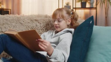 Gözlüklü genç kız masal kitapları okuyarak komik kısımlara gülümseyerek evinde dinleniyor. Çocuk aniden iç çeker olaylar ciddileştiğinde her sayfanın tadını sessizce çıkararak.