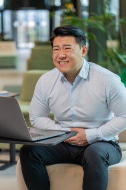 İş sırasında ofis lobisindeki dizüstü bilgisayarda aşırı yemek yiyen hasta Çinli iş adamı hayal kırıklığına uğradı. Acı çeken, karın ağrısı, kramp ve zehirlenme geçiren hasta bir menajer.