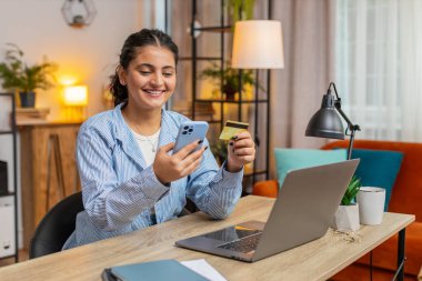 Merkez ofisteki online alışveriş ödemeleri için banka kartı ve akıllı telefon kullanan mutlu Hintli kadın serbest çalışan. İş anlaşması. E-bankacılık uygulaması ile gülümseyen kız alışverişi. Yaşam biçimi