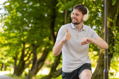 Kaçak akıllı saat zamanlayıcısı çalıştırıyor ve çalışıyor. Adam koşmadan önce kalp atış hızını kontrol ediyor. Erkek kardiyo çalıştırmaya başlar. Şehir parkındaki spor bilekliğinin nabzını kontrol et..