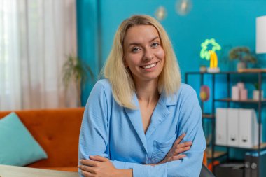 Ofis masasında kameraya bakan gülümseyen sarışın, beyaz iş kadınının portresi. Oturma odasındaki masada oturan serbest çalışan bir bayan. Mavi elbiseli kız..