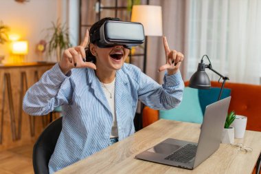 Evde ofis masasında otururken VR kulaklığı test eden Hintli serbest çalışan sürpriz bir kadın. Evde uzaktan kumanda ile çalışan genç işadamı kız sunum yapıyor. Yaşam biçimi.