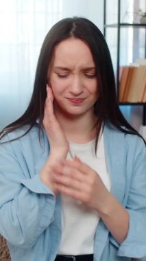 Şiddetli diş ağrısından muzdarip genç hasta kadın, yanağını tutuyor, yorulmadan ağrı kesici haplar arıyor. Kafkasyalı hasta kız diş ağrısından bitkin düşmüş.