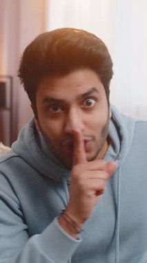 Sessiz olun lütfen. Genç Hintli bir adamın portresi işaret parmağını dudaklara bastırıyor. Sessiz jest işareti yapıyor. Gizli saklı konuşma, gizli mahremiyet. Sınıftaki kanepede oturan adam..