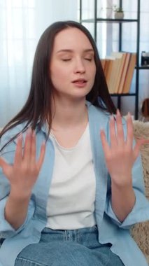 Evdeki genç kadın üzgün ve hayal kırıklığına uğramış bir şekilde kanepede oturuyor. Hatasından dolayı hayal kırıklığına uğramış bir şekilde facepalm hareketi yapıyor. Beyaz kız tatminsizlik, duygusal pişmanlık ve mutsuz duygular gösteriyor..