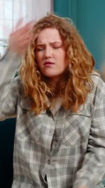 Evde genç bir kadın hayal kırıklığı ve duygusal hayal kırıklığı gösteren facepalm jestleri yapıyor. Kanepedeki beyaz saçlı kız üzgün, hata sonucu cesareti kırılmış, problem ya da beklenmeyen kötü sonuç.