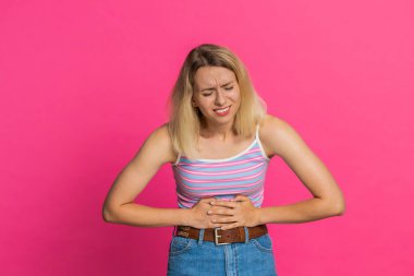 Adet sancısı çeken hasta bir genç kadın, karın ağrısı, karın ağrısı, karın ağrısı ya da regl ağrısı. Karın ağrısı, mide iltihabı, ishal, hazımsızlık. Pembe arka plandaki kız