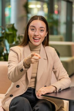 Seni seçiyorum. Kafkasyalı genç iş kadını yazılım geliştirici kamerayı işaret ederek, mutlu bir ifadeyle bakarak, işe alma seçimini yapıyor. Ofis lobisinde serbest çalışan kız..