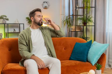 Tatmin olmuş beyaz tenli bir adam evinde, kanepede oturup sağlıklı bir hayat sürüyor, bir bardak saf su içiyor, gülümsüyor. Her gün su iç. Odadaki adam kameraya gülümsüyor..