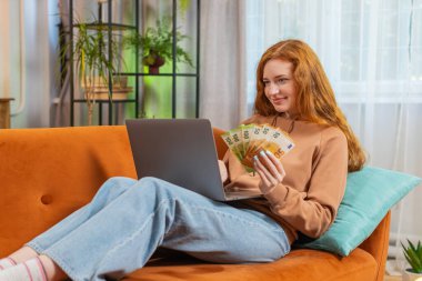 Planlama bütçesi. Zengin, mutlu, genç bir kadın. Dizüstü bilgisayarla nakit para sayıyor. Kanepede oturan faturaları hesaplıyor. Gelir maaşından memnun bir kız planlı tatil ve hediyeler için para biriktiriyor.