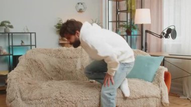 Yorgun Arap genç adam oturma odasındaki kanepede dinlenmenin keyfini çıkarıyor. Mutlu Lübnanlı adam kanepede uzanmış, dinleniyor, yorucu bir günün ardından uyukluyor, gözlerini kapıyor, elini başının arkasına koyuyor, stresten uzak.