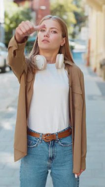 Hoşlanmamak. Kafkasyalı genç bir kadının baş parmağıyla işaret hareketi yapması hoşnutsuzluğunu dile getirmesi, tatminsiz kötü işler yapması, açık havada hata yapması. Şehir caddesinde hoşnutsuz bir kadın. Dikey