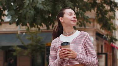 Mutlu genç bayan sabah kahvesinin tadını çıkarıyor sıcak bir içecek ve dışarıda gülümsüyor. Dinleniyorum, ara veriyorum. Diş teli takmış bir kız şehir merkezinin caddesinde yürüyor, kahve içiyor.