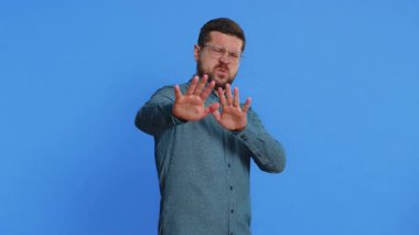 Buna bakmak istemiyorum, çok kötü. Gözlüklü, beyaz, orta yaşlı bir adamın elinde dur hareketi göstererek gözlerini kapamasından korkmuş, kafası karışmış, utangaç, izlemeyi reddeden. Mavi arkaplanda izole edilmiş adam