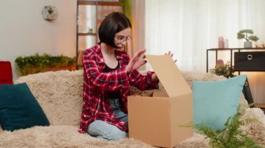 Genç, mutlu bir kadın paketini evdeki koltukta açar. Yeni gelen eşyalara bakarken mutlu bir şekilde gülümser. Kız neşe ve heyecanla tepki veriyor, alışveriş sonuçlarından ve hoş sürprizlerden zevk alıyor..