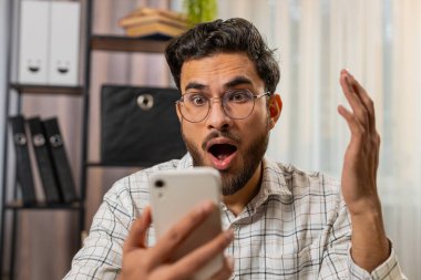 Aman Tanrım, vay canına. Akıllı telefon üzerinde çalışan genç ve şaşkın İspanyol işadamı aniden kazanılan galibiyet, piyango golü başarısı ve iyi haberler karşısında şok oldu. Merkez ofisteki Hintli serbest çalışan adam..